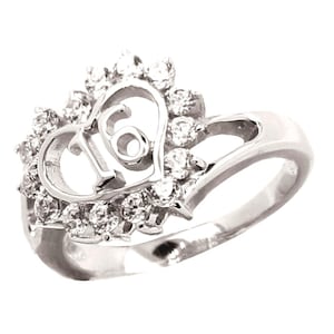 May include: A silver ring with a heart-shaped design featuring the number "16" surrounded by small clear stones.
