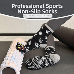 May include: Black non-slip sports socks with white patterns and a gray cuff. The socks are designed for yoga, Pilates, fitness, and aerobics. The image also shows a foam roller.