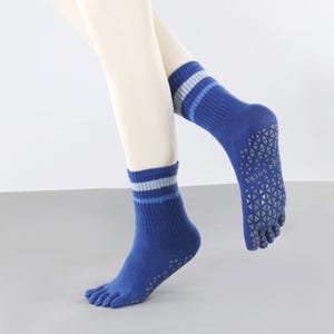 May include: Blue yoga socks with a striped cuff and a textured sole. The socks have individual toe slots and the words "yoga socks" printed on the sole. The socks are on a mannequin leg.