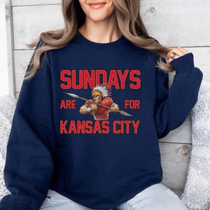 A woman wearing a navy blue sweatshirt with a graphic design and text printed on it.