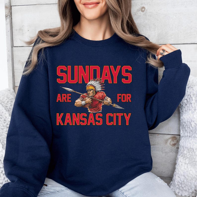 A woman wearing a navy blue sweatshirt with a graphic design and text printed on it.