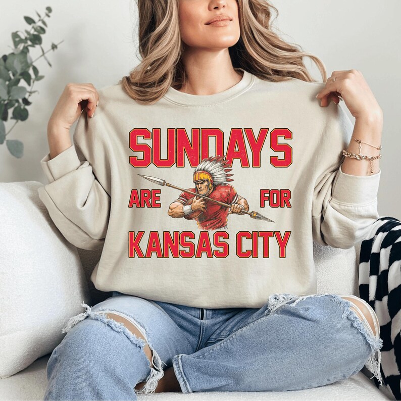 A woman wearing a white sweatshirt with a graphic design and text printed on it.