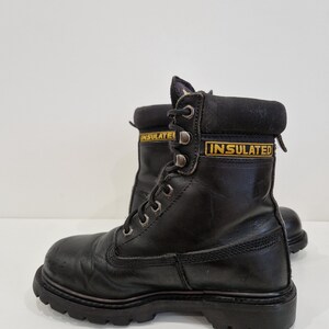 Puede incluir: Par de botas de trabajo de cuero negro con suela resistente. Las botas tienen ojales met&aacute;licos para los cordones y la palabra "INSULATED" en letras amarillas en el cuello. Las botas est&aacute;n dise&ntilde;adas para la durabilidad y la protecci&oacute;n.