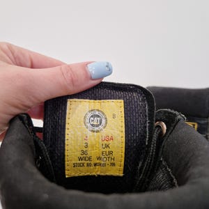 Puede incluir: Una taza de cer&aacute;mica blanca con un asa negra y el texto "But First, Coffee" en negro y negrita. La taza est&aacute; sobre una superficie de madera. La taza mide aproximadamente 10 cm de alto.