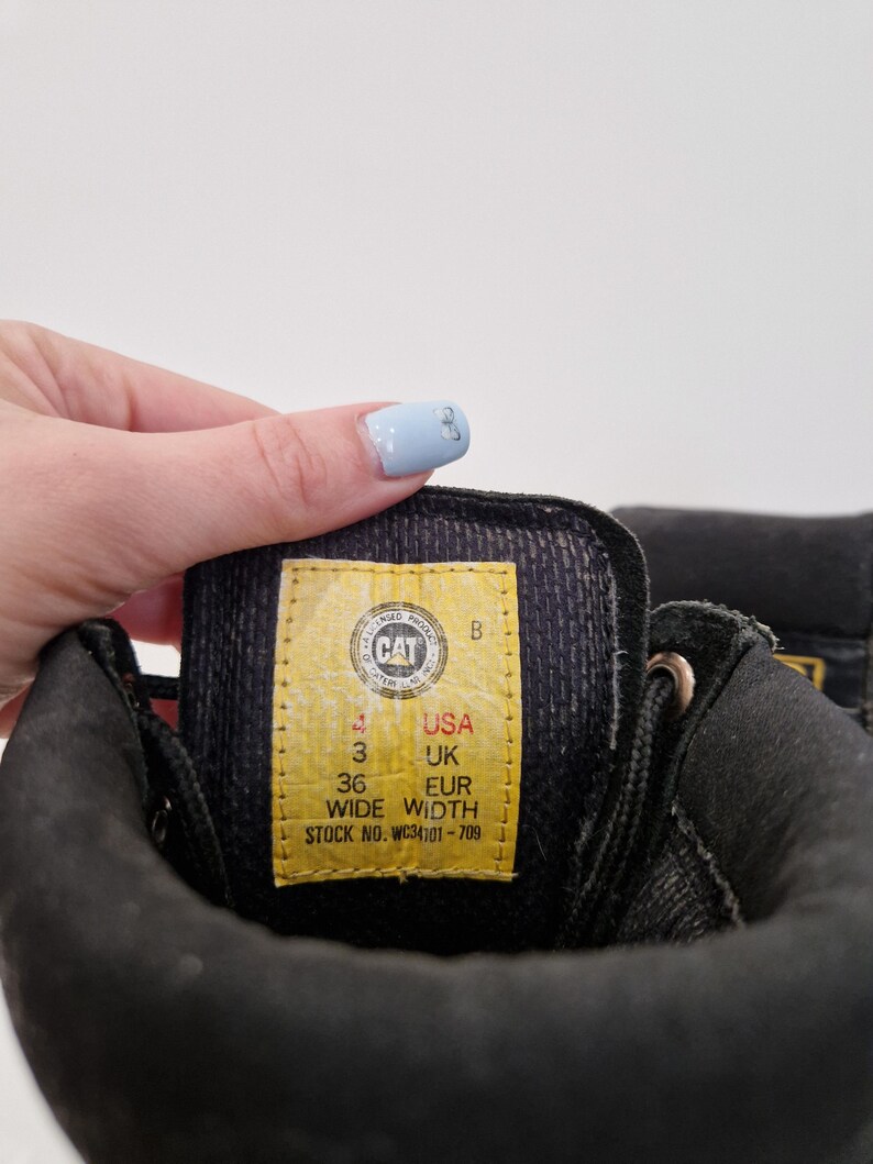 Puede incluir: Una taza de cer&aacute;mica blanca con un asa negra y el texto "But First, Coffee" en negro y negrita. La taza est&aacute; sobre una superficie de madera. La taza mide aproximadamente 10 cm de alto.