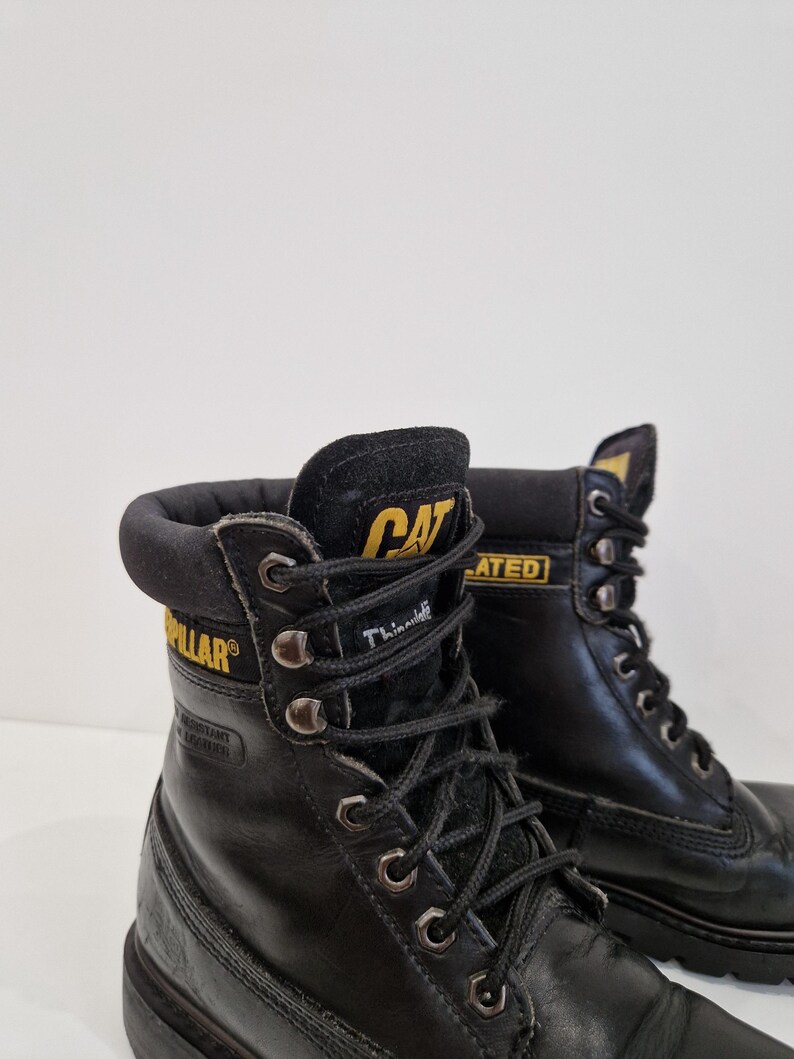 Puede incluir: Botas de trabajo de cuero negro con el logotipo CAT en amarillo. Las botas tienen cordones negros, ojales met&aacute;licos y un cuello acolchado. Las botas est&aacute;n dise&ntilde;adas para el trabajo y tienen una construcci&oacute;n duradera.