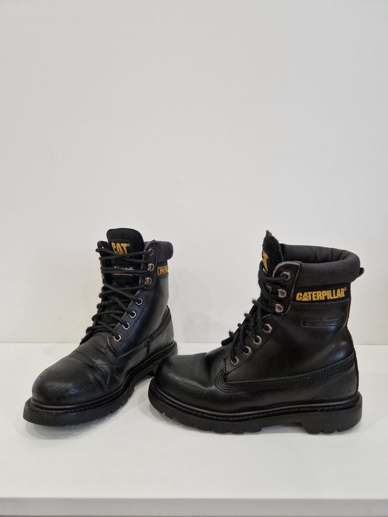 Puede incluir: Una taza de cer&aacute;mica blanca con un asa negra y el texto "But First, Coffee" en negro, con una fuente de estilo manuscrito. La taza est&aacute; sobre una superficie blanca.