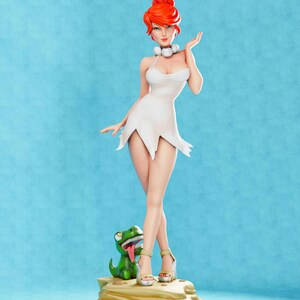 May include: A red-haired woman in a white dress stands on a rock with a green dinosaur figurine. The woman is wearing white heels and has a pearl necklace.