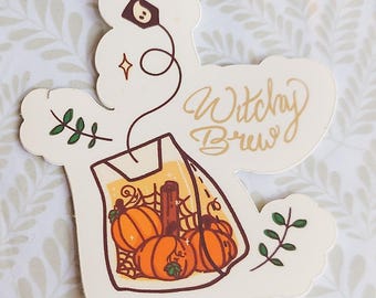 Peut inclure: Autocollant avec l'inscription "Witchy Brew" en lettres dorées. Le motif représente un sachet de thé avec des citrouilles à l'intérieur. Des brins verts et une étoile ornent le dessin. L'autocollant est sur un fond à motifs.