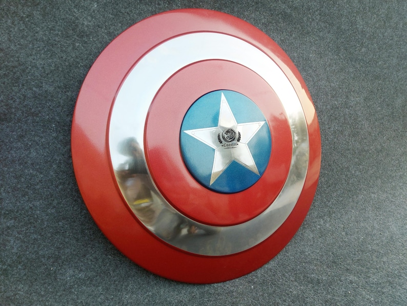 Op de afbeelding: Een rood, wit en blauw Captain America schild met een zilveren metalen rand. Het schild heeft een vijfpuntige ster in het midden met een blauwe achtergrond. De ster heeft een klein logo in het midden.
