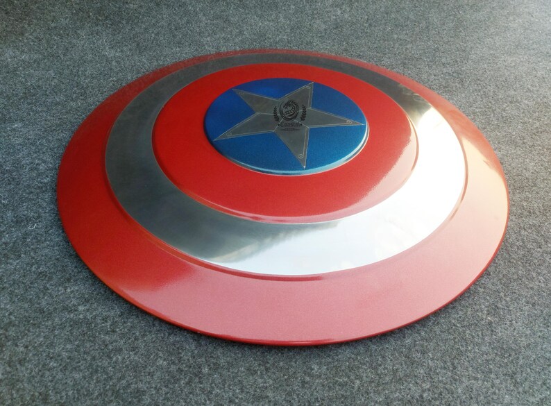 Op de afbeelding: Een rood, wit en blauw Captain America-schild met een vijfpuntige ster in het midden. Het schild heeft een zilveren metalen rand.