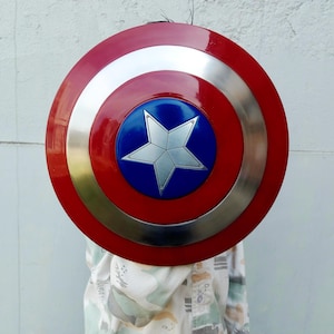 May include: A circular shield in red, silver, and blue. It has a central blue disc with a silver star, encircled by rings of red, silver, and a gold-coloured ring. This shield is a prop.