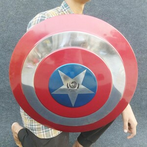 Op de afbeelding: Een rood, wit en blauw Captain America schild met een vijfpuntige ster in het midden. Het schild is gemaakt van metaal en heeft een glanzende afwerking.