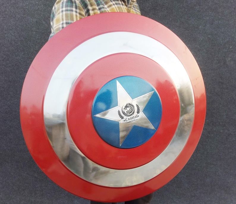 Op de afbeelding: Een rood, wit en blauw Captain America schild met een zilveren metalen rand. Het schild heeft een vijfpuntige ster in het midden met een blauwe achtergrond en een zilveren drakenlogo met de tekst "Coastal" eronder.