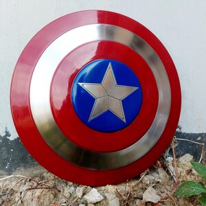 May include: A circular shield in red, silver, and blue. The centre features a silver star on a blue background, encircled by a silver band. The outer edge is red, creating a striking design.