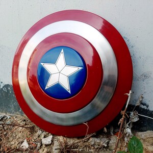 May include: A circular shield in red, white, and blue. The design includes a central blue disc with a white star, encircled by silver and red bands. This shield is likely a prop or collector's item.