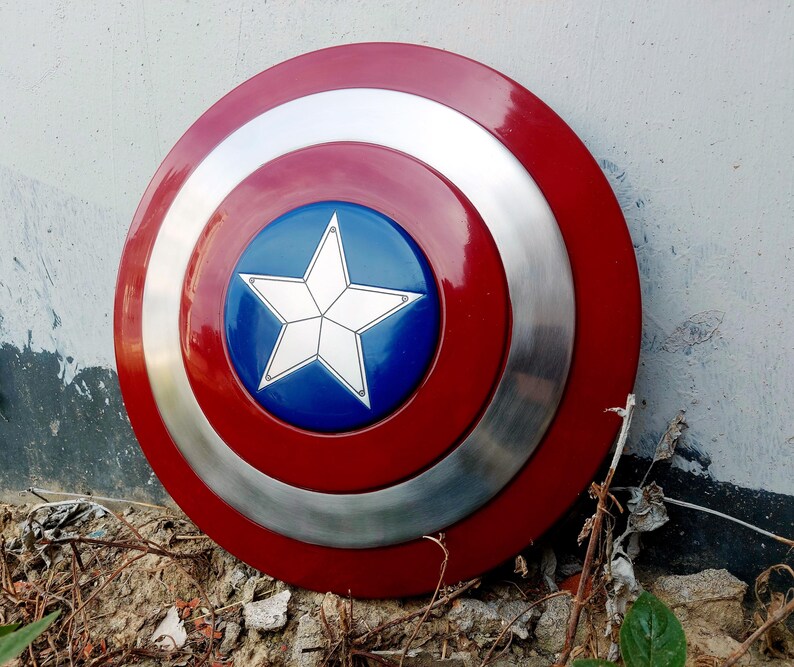 May include: A circular shield in red, white, and blue. The design includes a central blue disc with a white star, encircled by silver and red bands. This shield is likely a prop or collector's item.