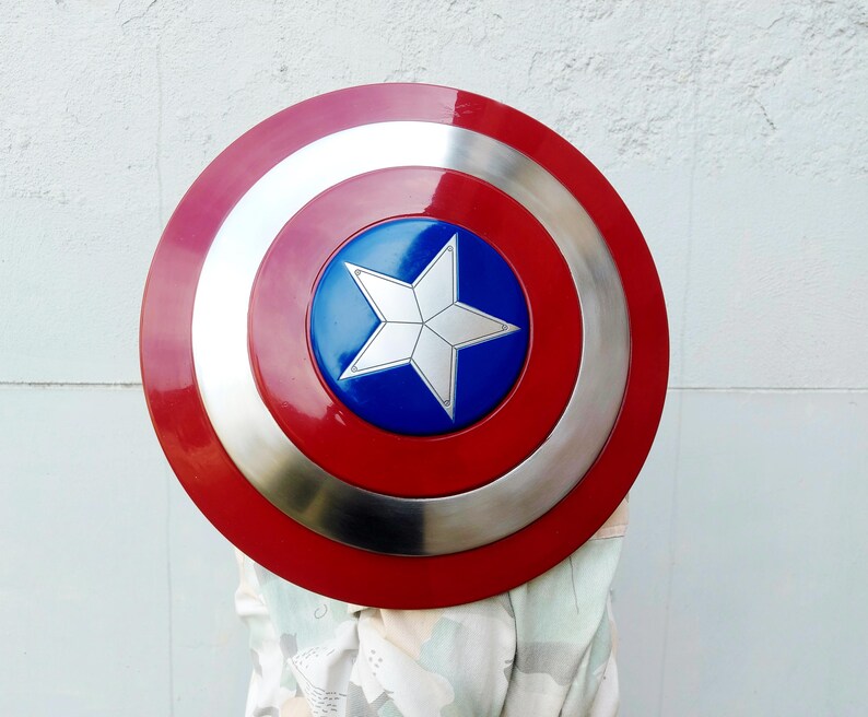 May include: A circular shield featuring a red border, a silver band, and a blue central disc with a white star. This shield is a replica of Captain America's shield, a well-known superhero accessory.