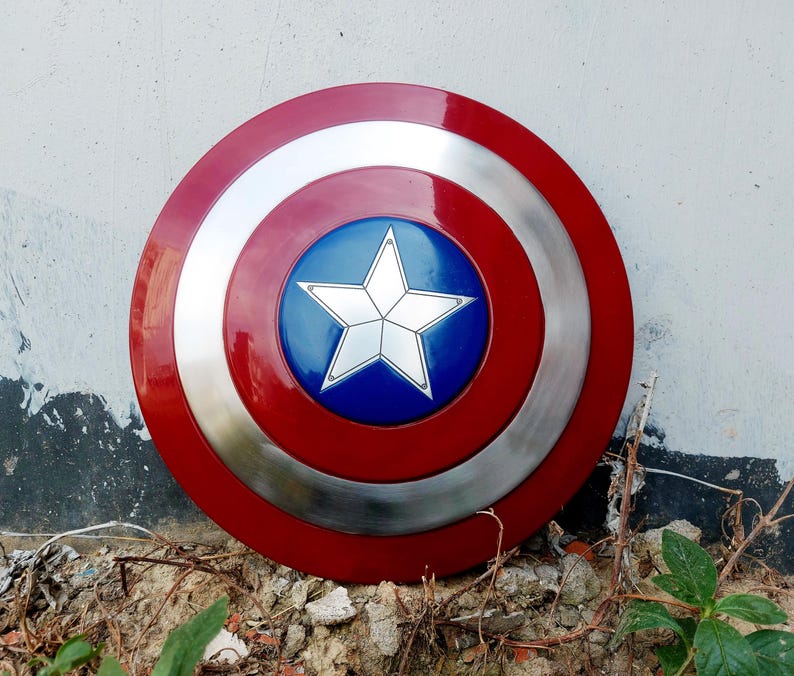 May include: A circular shield in red, silver, and blue. It has a central blue disc with a white star, encircled by silver and red rings. This shield is likely a prop or collectible item.