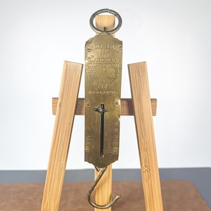 Peut inclure: Une balance à ressort en laiton vintage dotée d'un anneau de suspension circulaire en haut et d'un crochet incurvé en bas. La face métallique est gravée avec le texte FAMILY SCALE, LANDERS IMPROVED et WARRANTED, avec une échelle de mesure verticale.