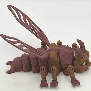 Puede incluir: Un juguete de insecto articulado marrón y rojo con alas, patas y una cabeza con ojos. El juguete está hecho de plástico y tiene un diseño detallado.