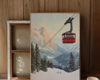 Puede incluir: Una impresión artística enmarcada representa un teleférico rojo ascendiendo sobre un paisaje montañoso nevado. La obra presenta una ilustración detallada del teleférico, árboles y montañas, con una paleta de colores cálidos. La impresión se muestra sobre un fondo de madera.
