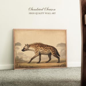 Op de afbeelding: Een ingelijste wandkunstprint met een hyena die door een savannelandschap loopt. De hyena heeft een gevlekte vacht en is afgebeeld in vintage stijl. De tekst "Sundried Season HIGH QUALITY WALL ART" staat bovenaan.