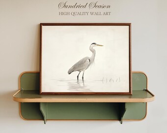 May include: A framed print of a heron standing in water, with a brown wooden frame. The artwork is displayed on a green and tan shelf. The text "Sundried Season" and "High Quality Wall Art" are above the framed print.