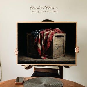 May include: A framed wall art print featuring a vintage-style depiction of the American flag draped over a wooden chest. The artwork has a dark, moody aesthetic, with the text "Sundried Season HIGH QUALITY WALL ART" at the top.