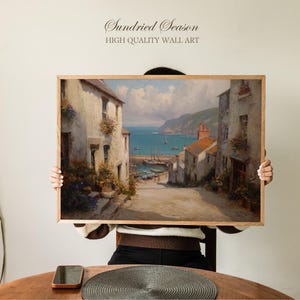 May include: A framed wall art print featuring a coastal town scene with buildings, a road, and a harbor. The artwork has a vintage aesthetic with muted colors and the text "Sundried Season HIGH QUALITY WALL ART" at the top.