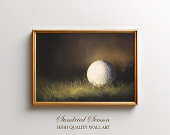 Op de afbeelding: Een ingelijste kunstafdruk met een golfbal in groen gras, in een gouden lijst. De tekst "Sundried Season HIGH QUALITY WALL ART" staat onderaan.
