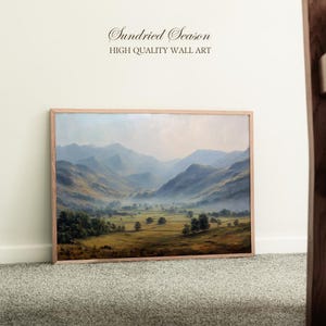 Puede incluir: Una impresión artística enmarcada que representa un paisaje de valle con montañas al fondo. La obra de arte tiene un marco de madera clara. El texto "Sundried Season HIGH QUALITY WALL ART" está en la parte superior.