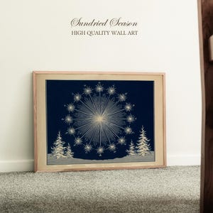 May include: Framed wall art with a vintage illustration of a starburst design and snowflakes on a dark blue background. The artwork includes two stylized evergreen trees and the text "Sundried Season HIGH QUALITY WALL ART".