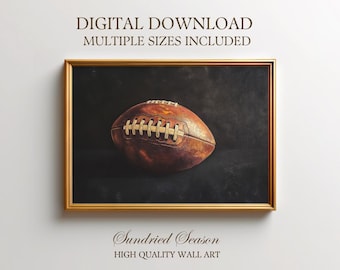 May include: A framed print featuring a vintage-style football against a dark background. The football is brown with white laces. The frame is gold. Text at the top reads "DIGITAL DOWNLOAD MULTIPLE SIZES INCLUDED". The bottom text reads "Sundried Season HIGH QUALITY WALL ART".
