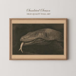 Könnte beinhalten: Ein gerahmter Wandkunstdruck mit einer sepiafarbenen Illustration eines Komodowarans mit herausgestreckter gespaltener Zunge. Der Text "Sundried Season" und "HIGH QUALITY WALL ART" steht über dem rechteckigen Holzrahmen in einer Serifenschrift.