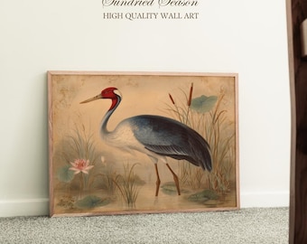 May include: Framed wall art featuring a crane in a wetland scene. The bird has a red head, blue wings, and long legs. The artwork includes the text "Sundried Season" and "HIGH QUALITY WALL ART". The background shows water, plants, and a pink flower.