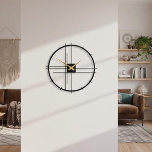 May include: A modern black and gold wall clock with a minimalist design. The clock features a circular frame with intersecting lines and gold hands. The clock is mounted on a white wall, adding a touch of contemporary style to the room.