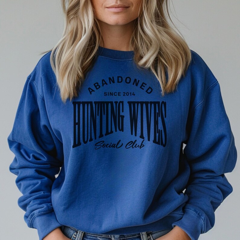 May include: A royal blue sweatshirt with the text "Abandoned Since 2014 Hunting Wives Social Club" printed in black.