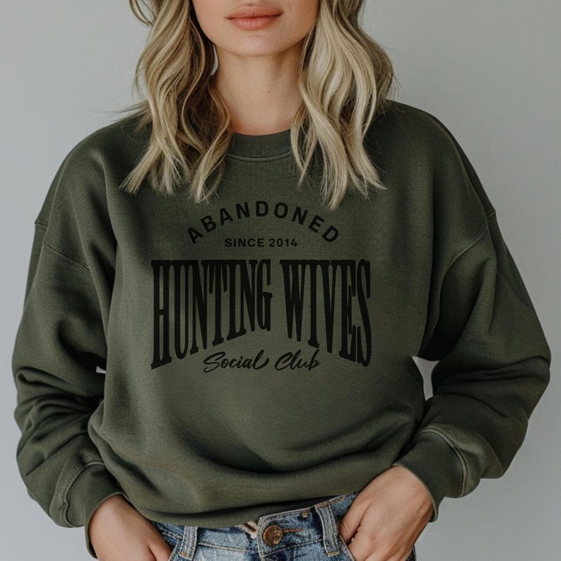 May include: A green sweatshirt with the text "Abandoned Since 2014 Hunting Wives Social Club" printed on the front.