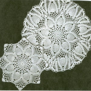 May include: Two white crocheted doilies, one round and one star-shaped, on a dark green background.