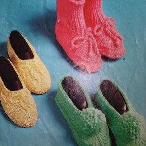 Puede incluir: Tres pares de zapatillas de punto en diferentes colores y estilos. El primer par es amarillo, el segundo par es verde y el tercer par es rosa.