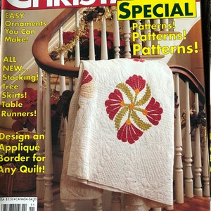 May include: A magazine cover featuring a white quilt with a red floral design. The magazine is titled "Christmas Special" and features the text "21 Patterns!" and "Make This Heirloom Christmas Quilt!"