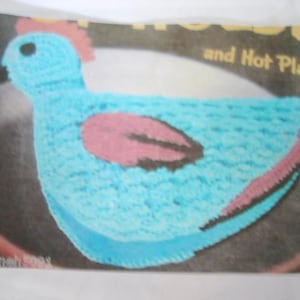 May include: A blue crocheted chicken hot pad with a pink and black wing design. The hot pad is on a black background with the text "and Hot Platter" visible.