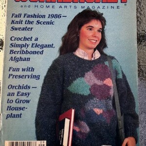 May include: The Workbasket magazine cover from September 1985 features a woman wearing a colorful knit sweater and holding a book. The cover text reads "Fall Fashion 1986 - Knit the Scenic Sweater" and "Crochet a Simply Elegant, Beribboned Afghan".