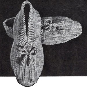 Peut inclure: Une paire de pantoufles en tricot gris avec un nœud et un pompon. Les pantoufles sont faites avec un fil doux et confortable et ont une coupe confortable.