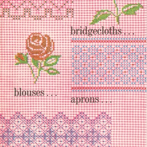 Op de afbeelding: Een roze en witte gingham stof met borduurmotieven in kruissteek. De ontwerpen omvatten een bloem, een rand en een geometrisch patroon. De tekst "for skirts... bridgecloths... blouses... aprons... cafe curtains..." is op de stof gedrukt.