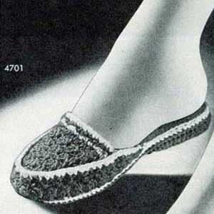 Op de afbeelding: Een close-up van een gehaakte pantoffel in lichtgrijs. De pantoffel heeft een eenvoudig ontwerp met een afgeronde teen en een platte zool.