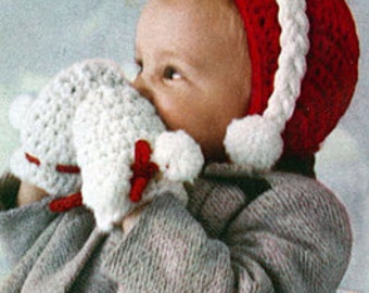 May include: A baby wearing a red and white crocheted Santa hat with white pom-poms. The baby is holding a white crocheted airplane toy with red accents.