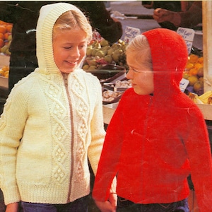 May include: Two children wearing knitted hooded sweaters. The girl on the left is wearing a cream-coloured sweater with a cable knit pattern. The girl on the right is wearing a red sweater.