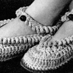 May include: A pair of crocheted slippers with a button detail on the ankle strap. The slippers are made in a light beige color.